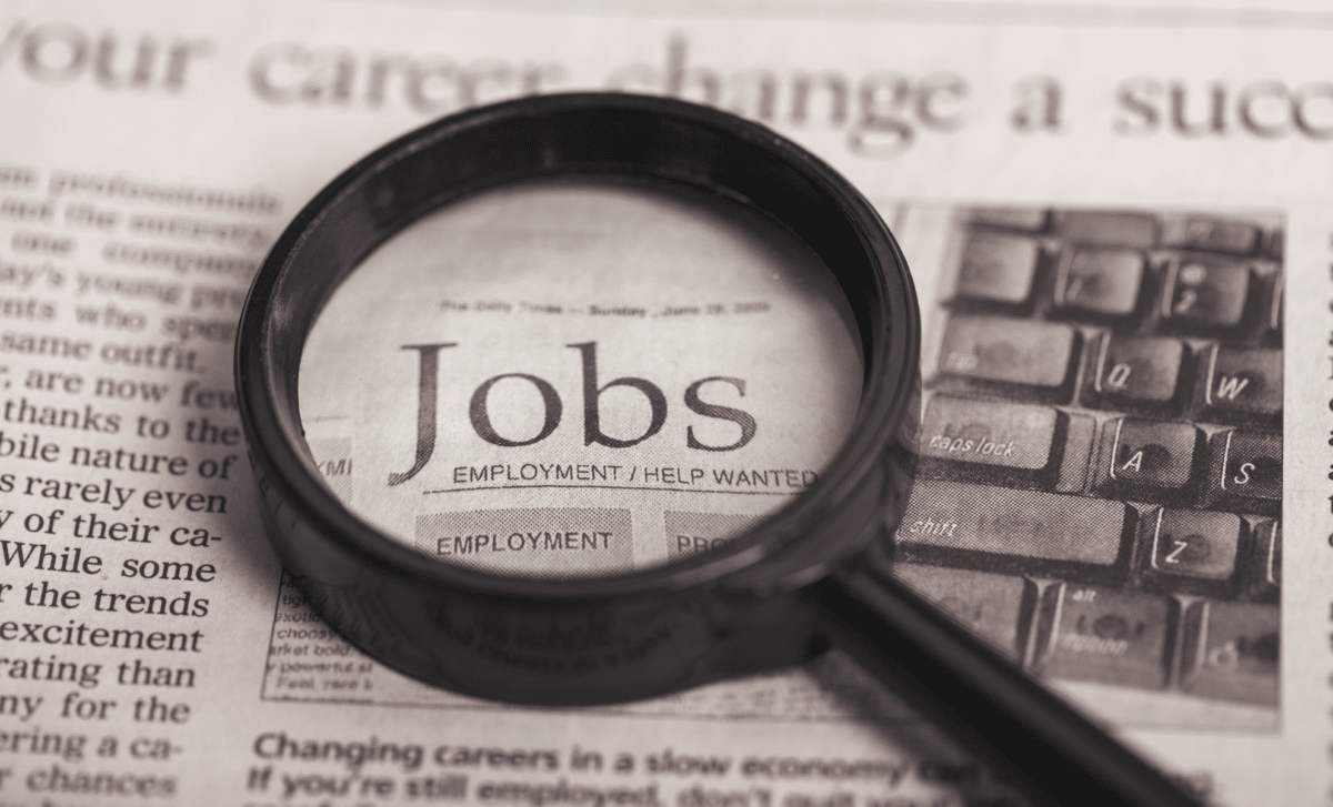 UK Job Market - Word "Jobs" Put in Bold Under Magnifying Glass on a Newspaper