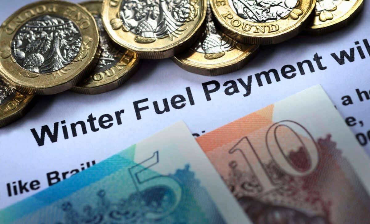 Close-up of Pound Coins on Top of A Piece of Paper that Reads "Winter Fuel Payment" along with £5 and £10 British Banknotes