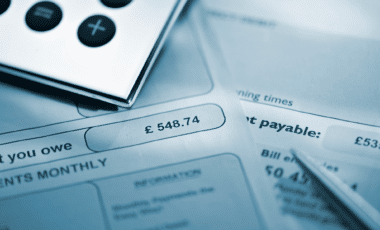 Blue Toned Image Of Silver Calculator And Pen On Household Bills