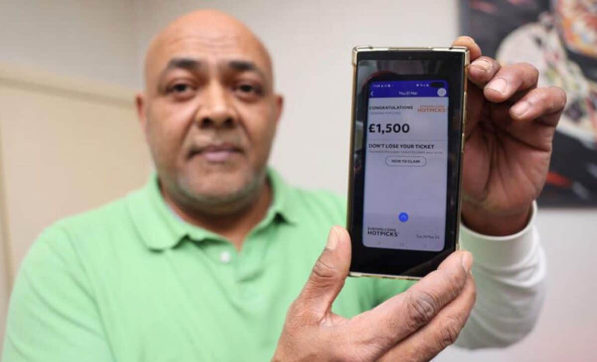 Sergei Cofie Squire Holding Up His Phone Where It Shows A Confirmation From The National Lottery That He Has Won Money.