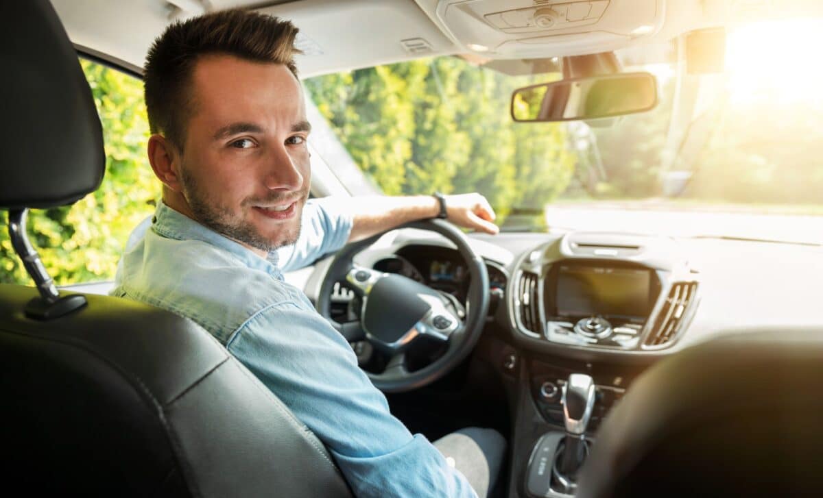 Young Man With Short Dark Hair And A Slight Beard, Smiling In The Driver's Seat