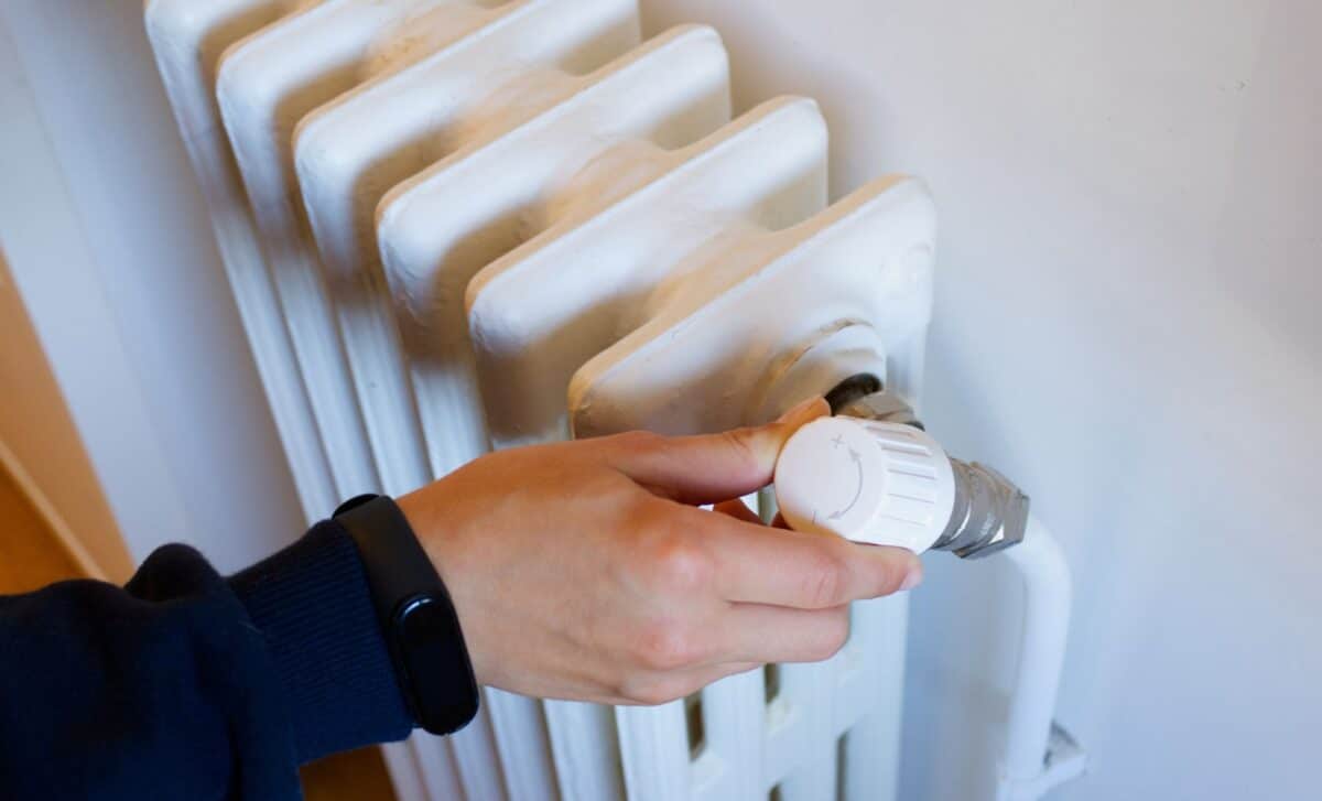 A Hand Turning The Knob On A Radiator