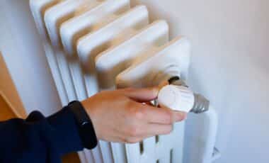 A Hand Turning The Knob On A Radiator