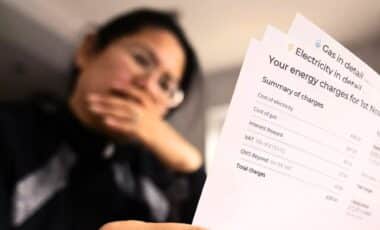 A Person Holding A Paper Titled 'your Energy Charges'