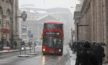 A Red London Bus Makes Its Way Through The Snow As A Snowstorm Descends On Central London.