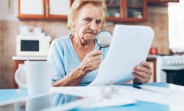 Elderly Woman Holding A Magnifying Glass Trying To Read A Paper