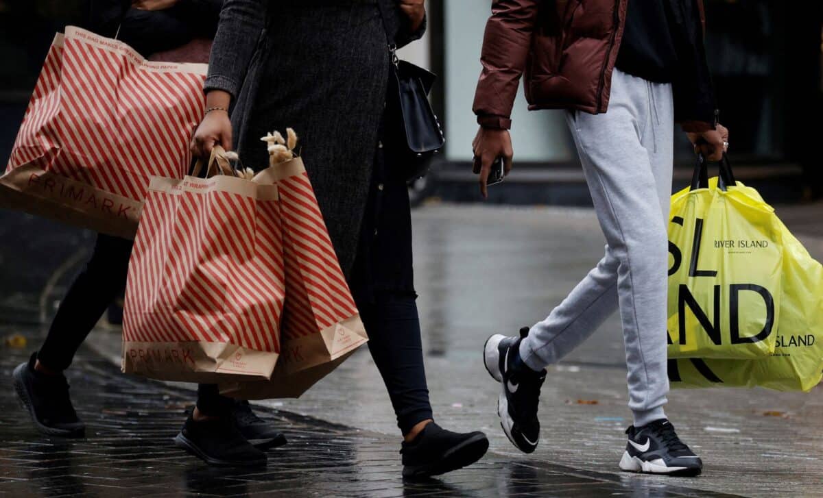 Two People Walking On A Wet Street Carrying Shopping Bags