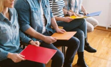 Young People Sitting in Chairs Holding Folders Waiting For A Job Interview