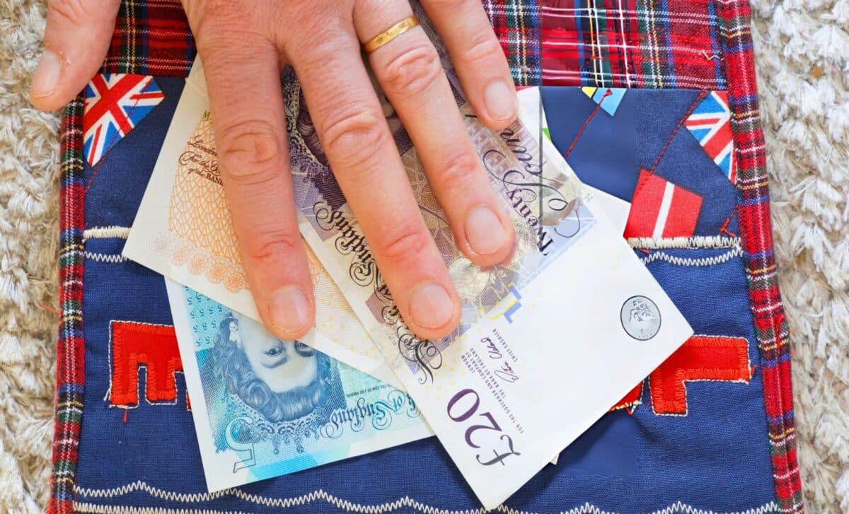 Hand on pound banknotes from Cost of Living Grants