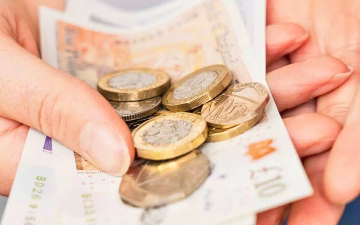 Winter Fuel Payment-Close-up of Hands Holding British Pound Coins and Banknotes