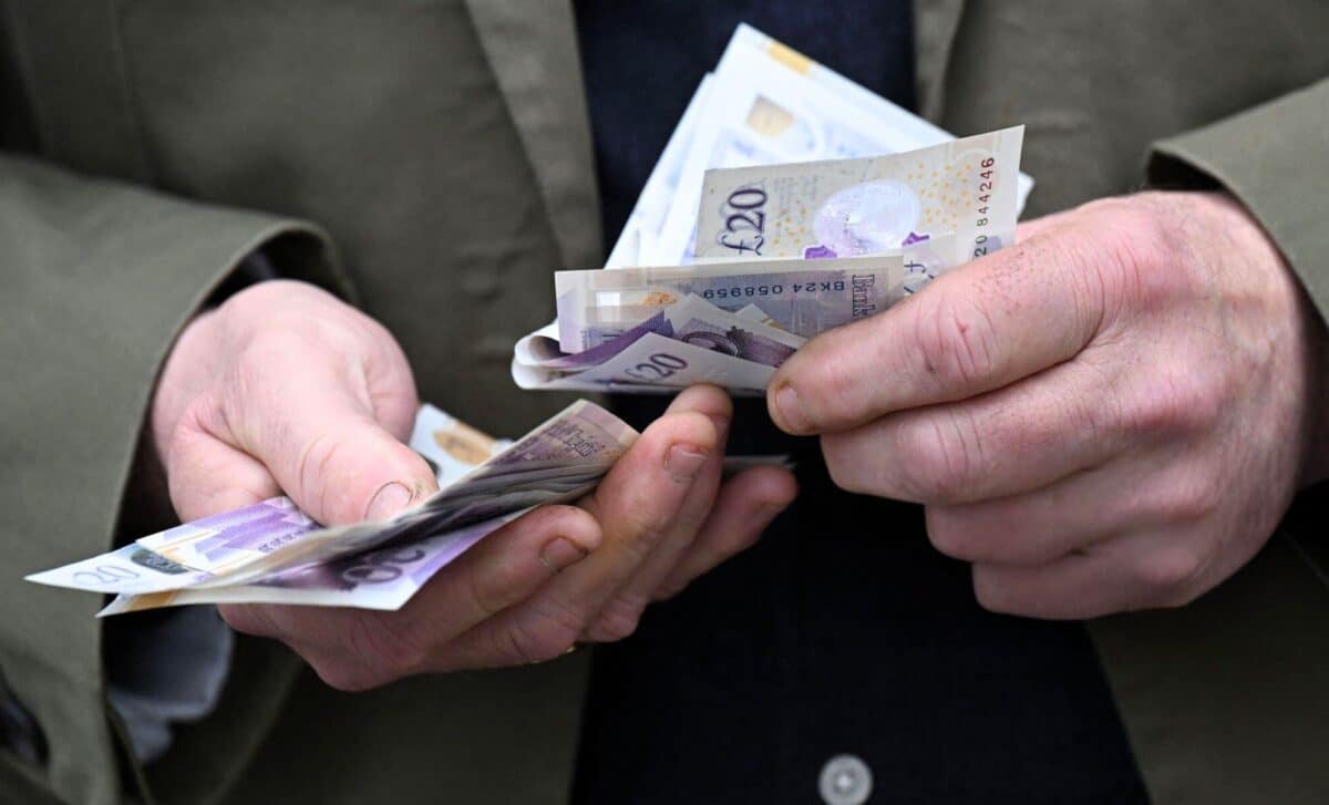 A State Pensioner Holds A Wad Of Pound Notes