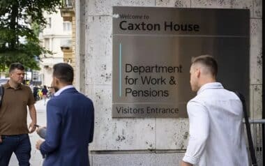 the exterior of Caxton House, home to the Department for Work and Pensions (DWP), with a prominent sign directing visitors to the entrance.