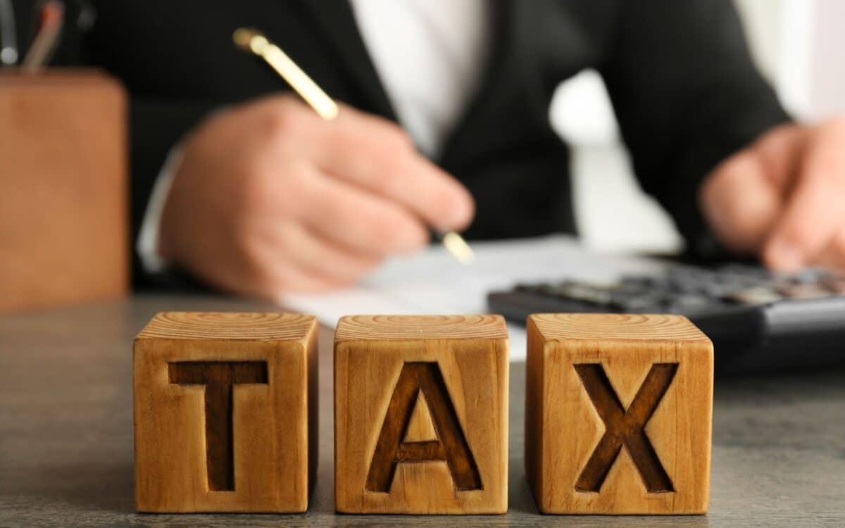 IRS-three wooden blocks spelling out the word TAX in capital letters. The blocks are placed on a desk or table