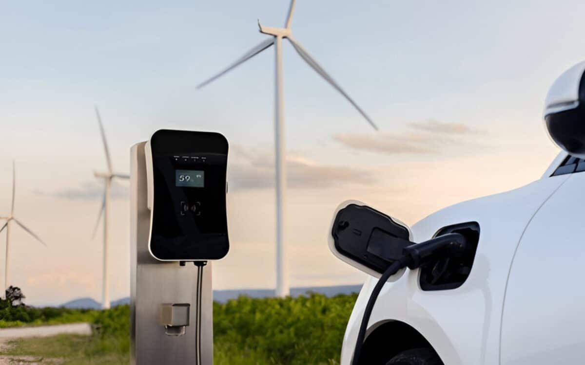 Trump-Electric vehicle (EV) charging station in a scenic outdoor setting. In the background, several large wind turbines are visible