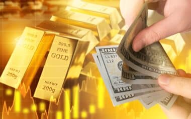 gold bars stamped with 999.9 Fine Gold and labeled with their weight of 200g, a hand is holding and flipping through U.S. $100 bills