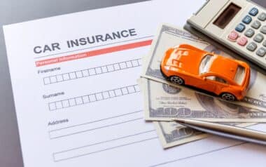A car insurance form is pictured alongside a toy vehicle