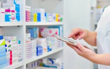 Pharmacist holding computer tablet in pharmacy drugstore