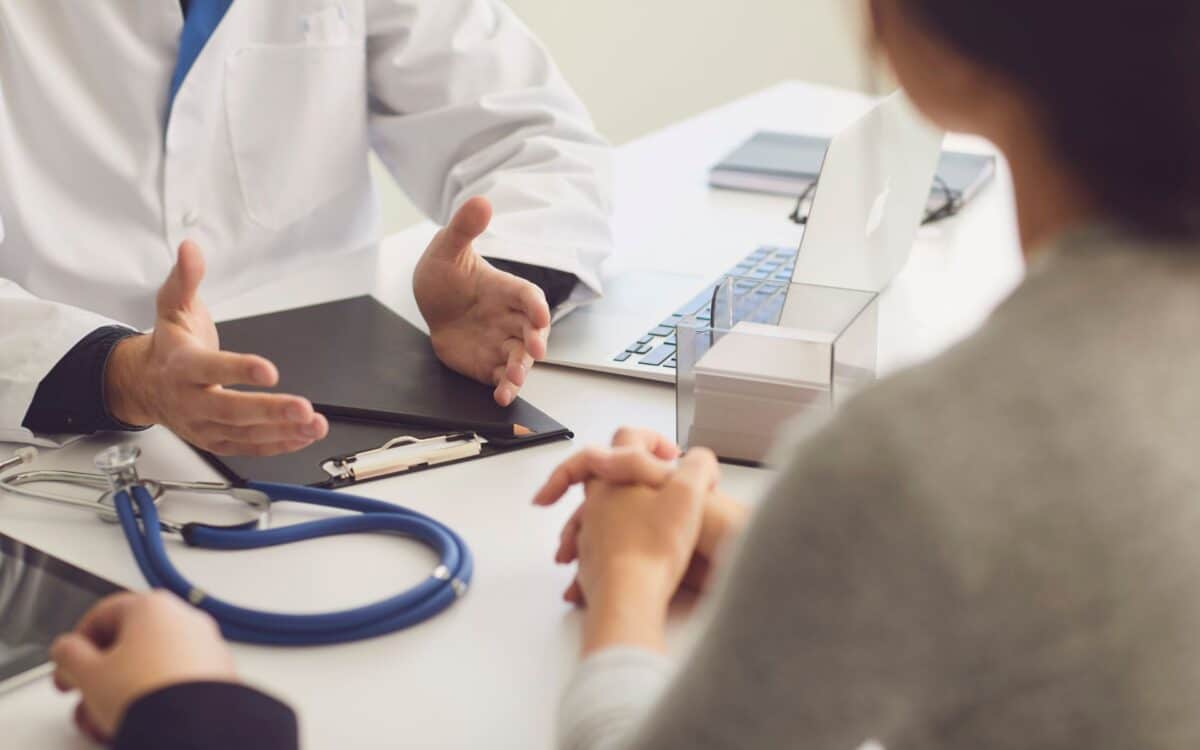 Doctor and Couple Patient Sitting at the Table in Clinic Office.