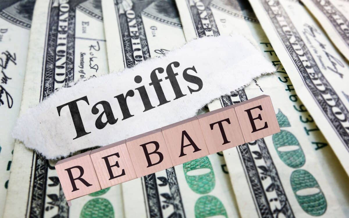 Tariffs newspaper headline on money et REBATE wooden word block on