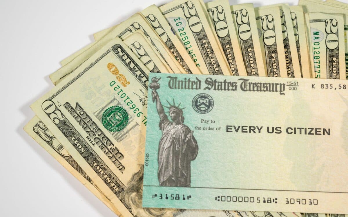 Stack of Twenty US Dollar Bills and Federal Stimulus Payment Check