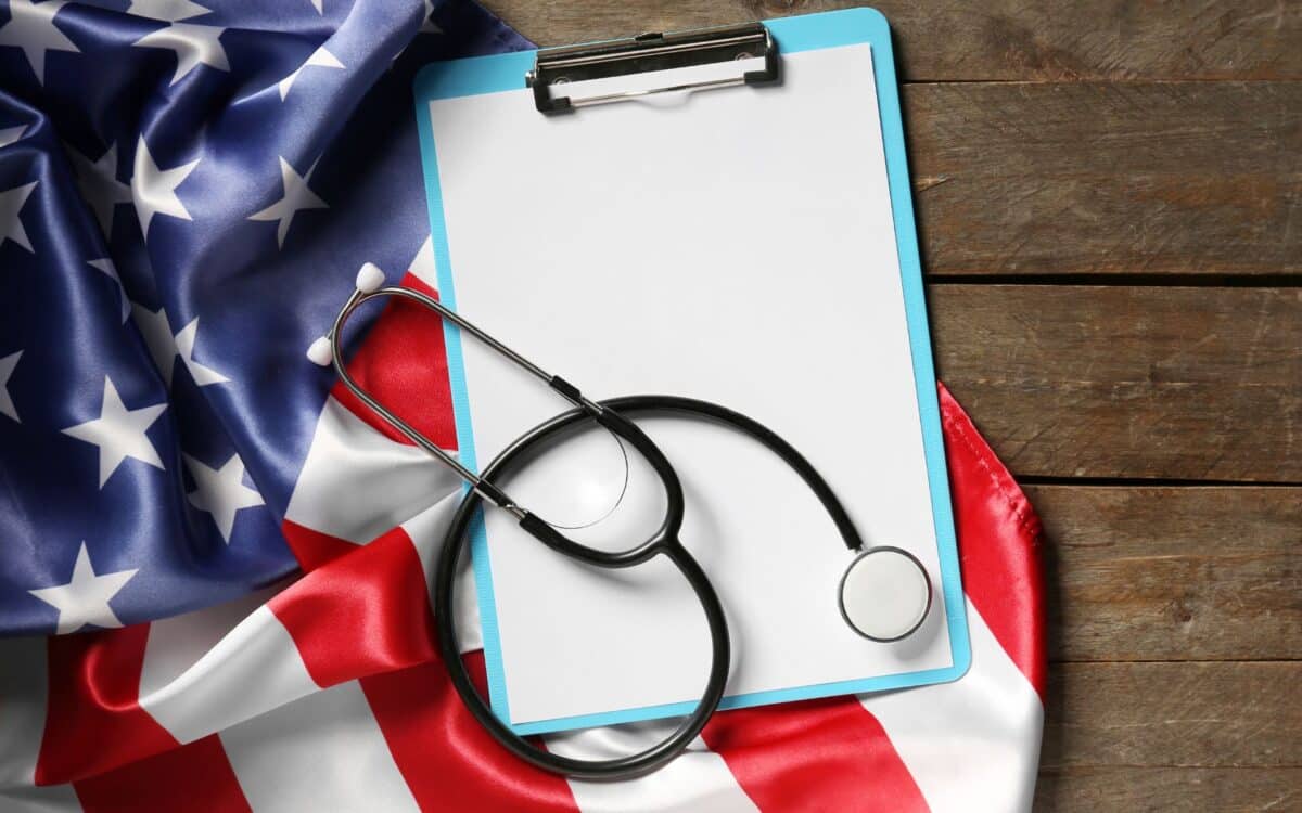 U.S. Flag with Stethoscope and Clipboard on Wooden Background