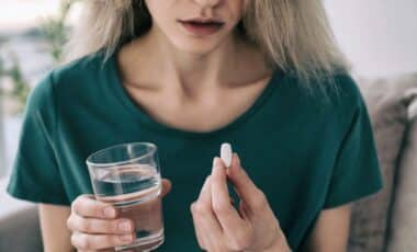Young Woman with Pill and Glass of Water