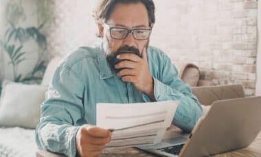 A man reading at home worried about having electricity or paying the bill while sitting in front of a laptop (1)