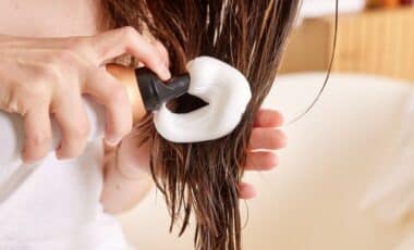 Woman applying hair mousse